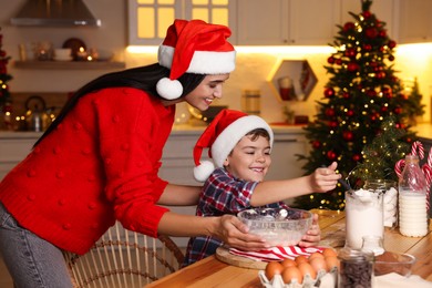 Happy mother and her son making dough for Christmas cookies at home