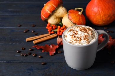 Photo of Cup with tasty pumpkin spice latte on blue wooden table
