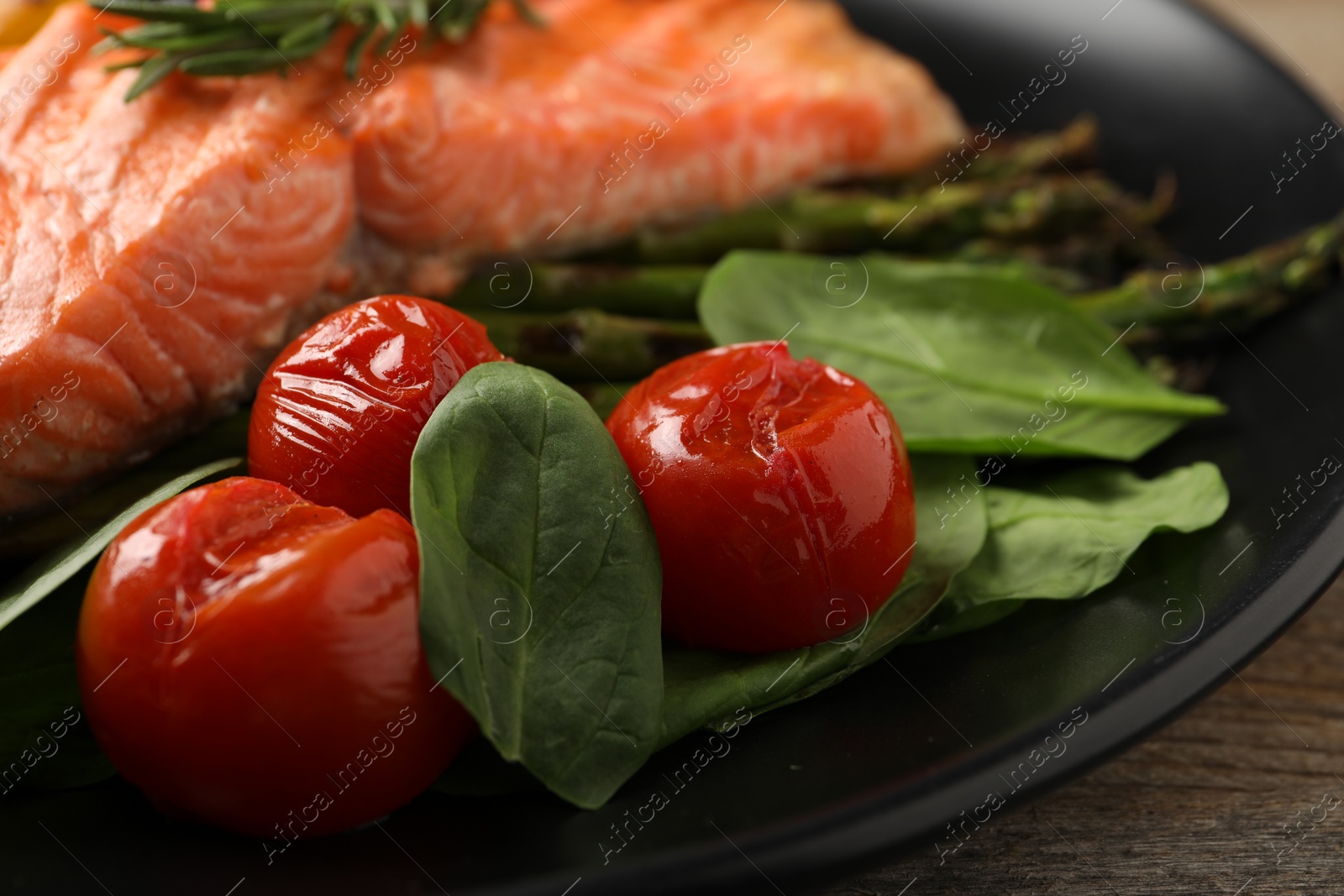 Photo of Tasty grilled salmon with tomatoes and spinach on plate, closeup