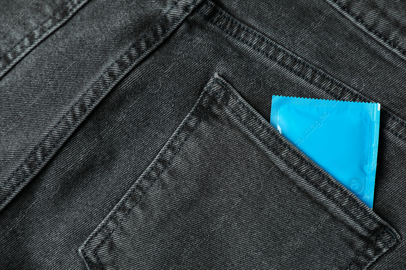 Photo of Packaged condom in dark jeans pocket, closeup. Safe sex