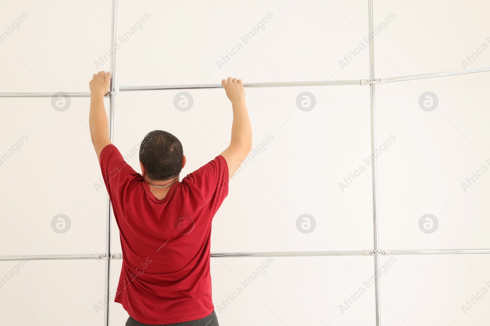 Photo of Worker installing new metal pipes indoors, back view