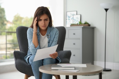 Worried woman reading paper letter at home