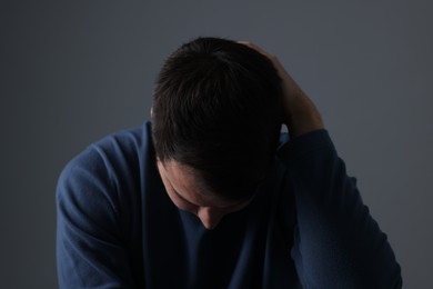 Photo of Sadness. Upset man on dark grey background