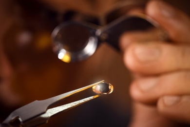 Photo of Jeweler working with gemstone on blurred background, closeup