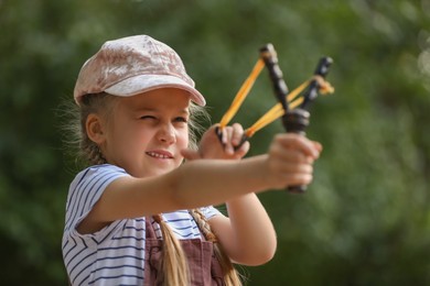 Photo of Little girl playing with slingshot in park
