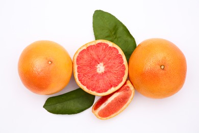 Photo of Fresh grapefruits and green leaves on white background, flat lay