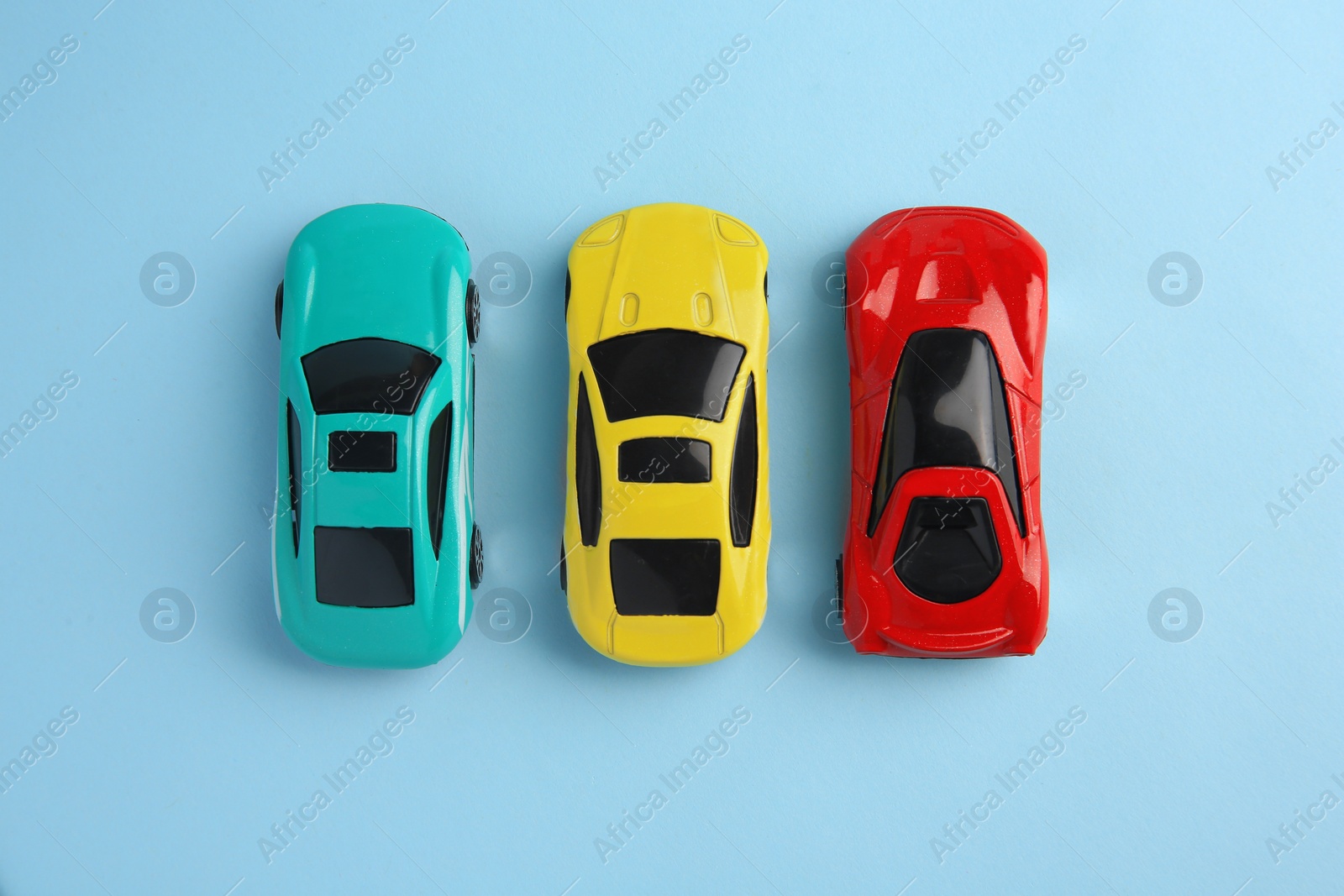 Photo of Different bright cars on light blue background, flat lay. Children`s toys