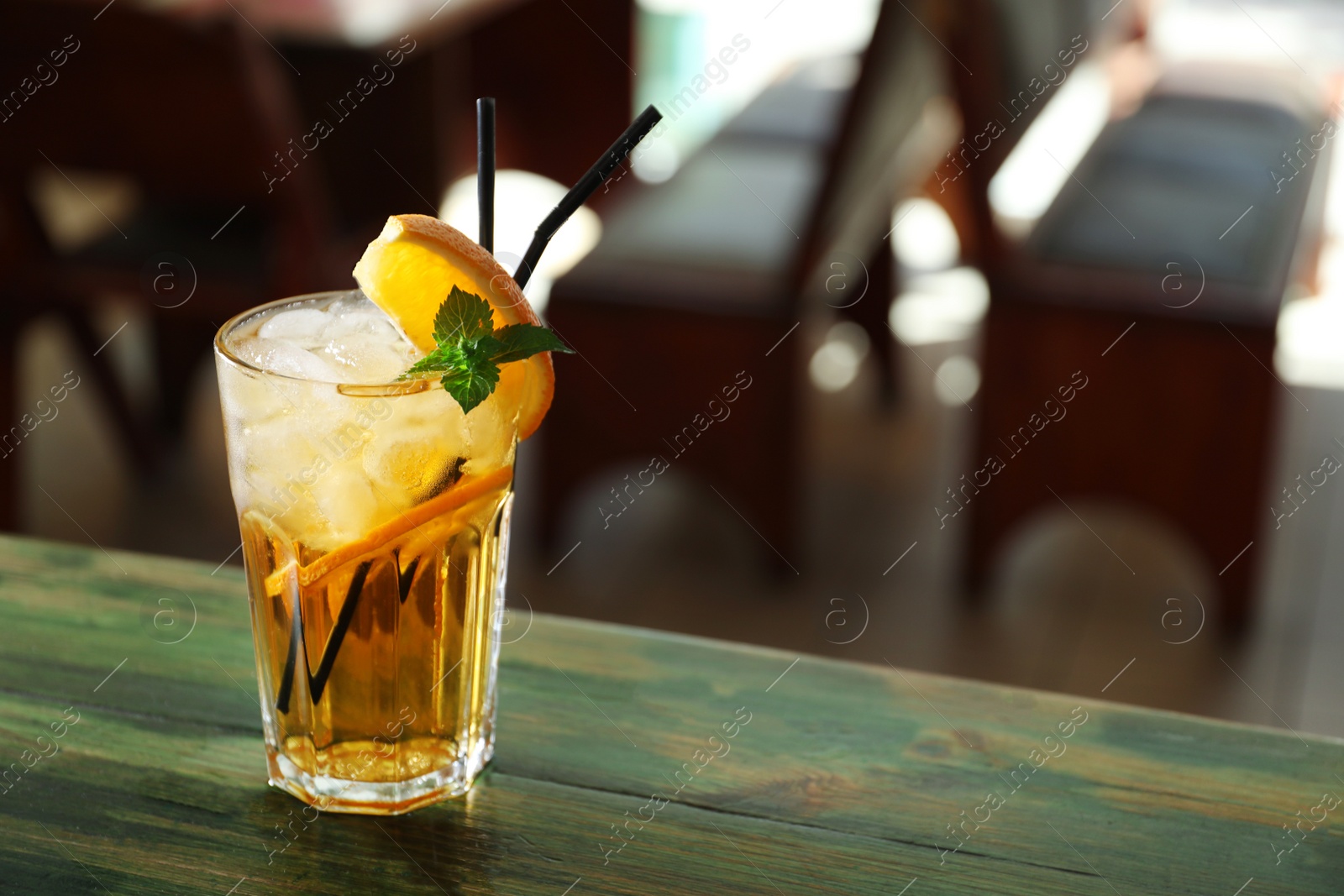 Photo of Glass of delicious cocktail with ice on table in bar