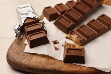 Photo of Tasty sweet chocolate bars with wooden board on white table