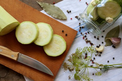 Photo of Cut fresh zucchini and other ingredients on wooden table, flat lay. Pickling vegetables