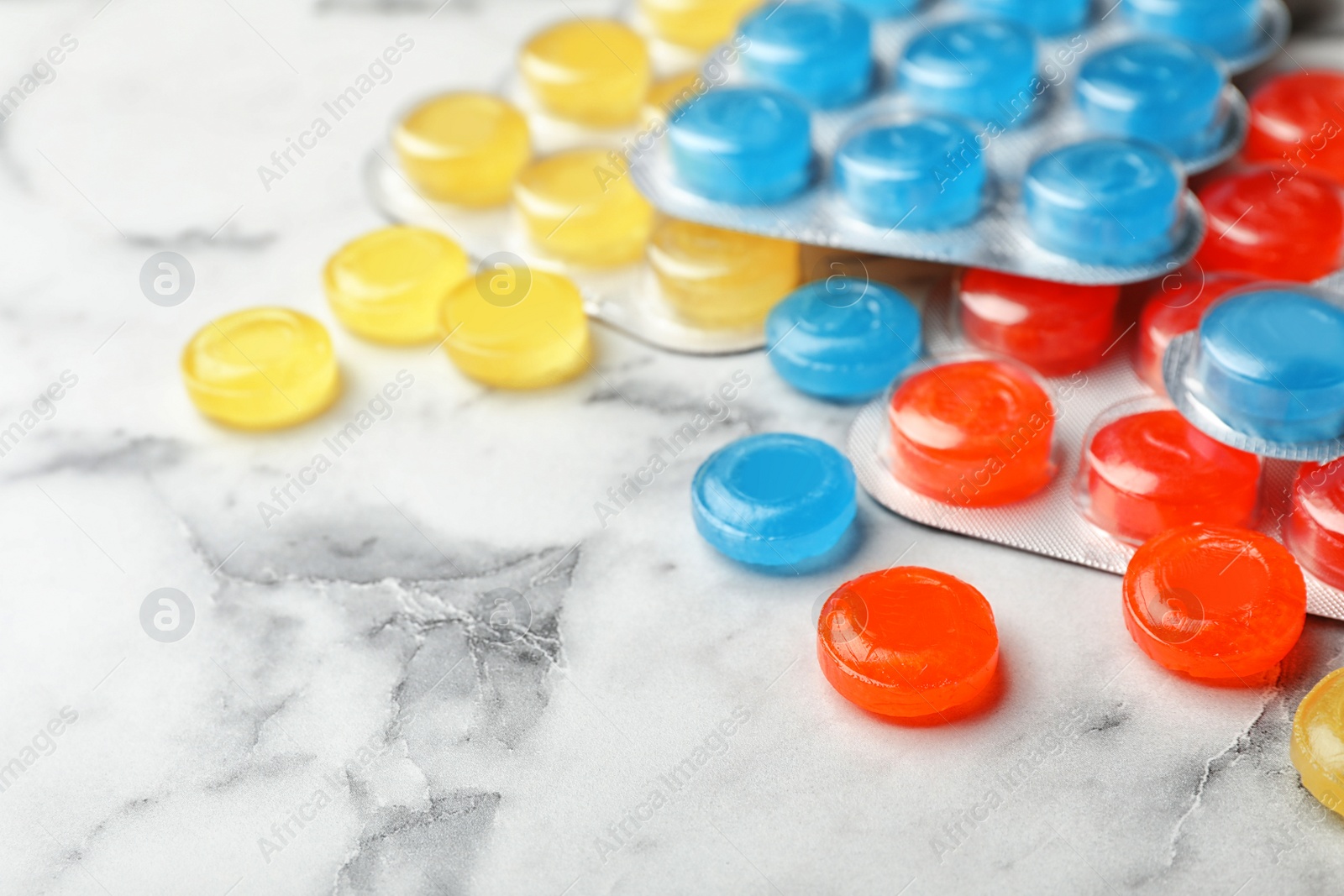 Photo of Color cough drops on marble background, closeup