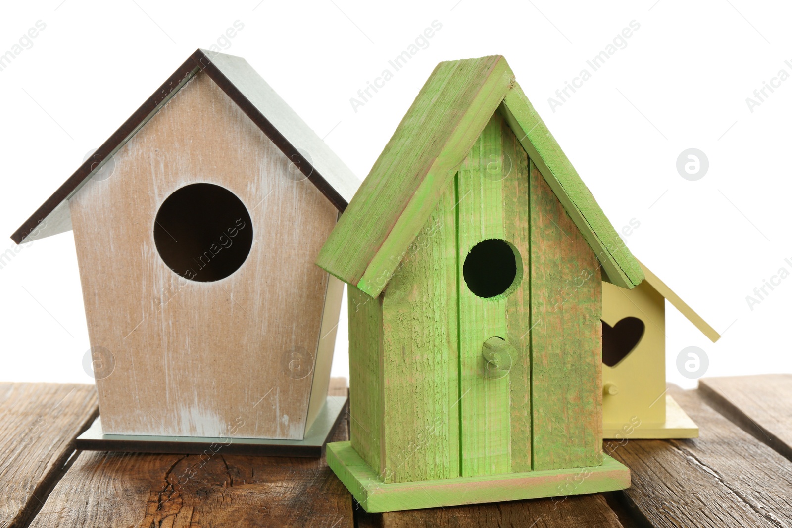 Photo of Three different bird houses on wooden table against white background