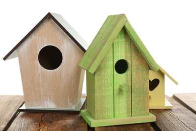 Three different bird houses on wooden table against white background