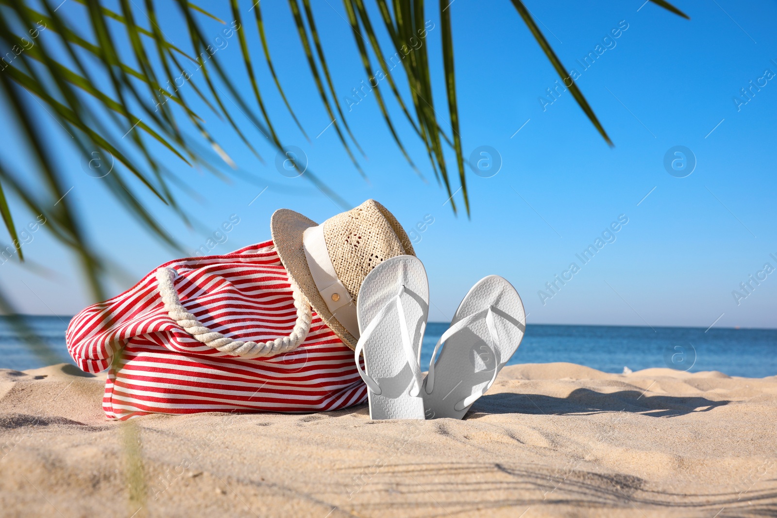 Photo of Set with stylish beach accessories on sand near sea