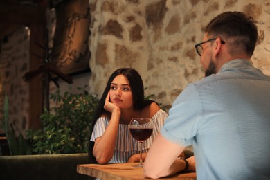 Photo of Young woman getting bored during date with man at cafe