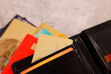 Many different credit cards and leather wallet on grey table, closeup