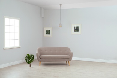 Living room interior with comfortable sofa near light wall