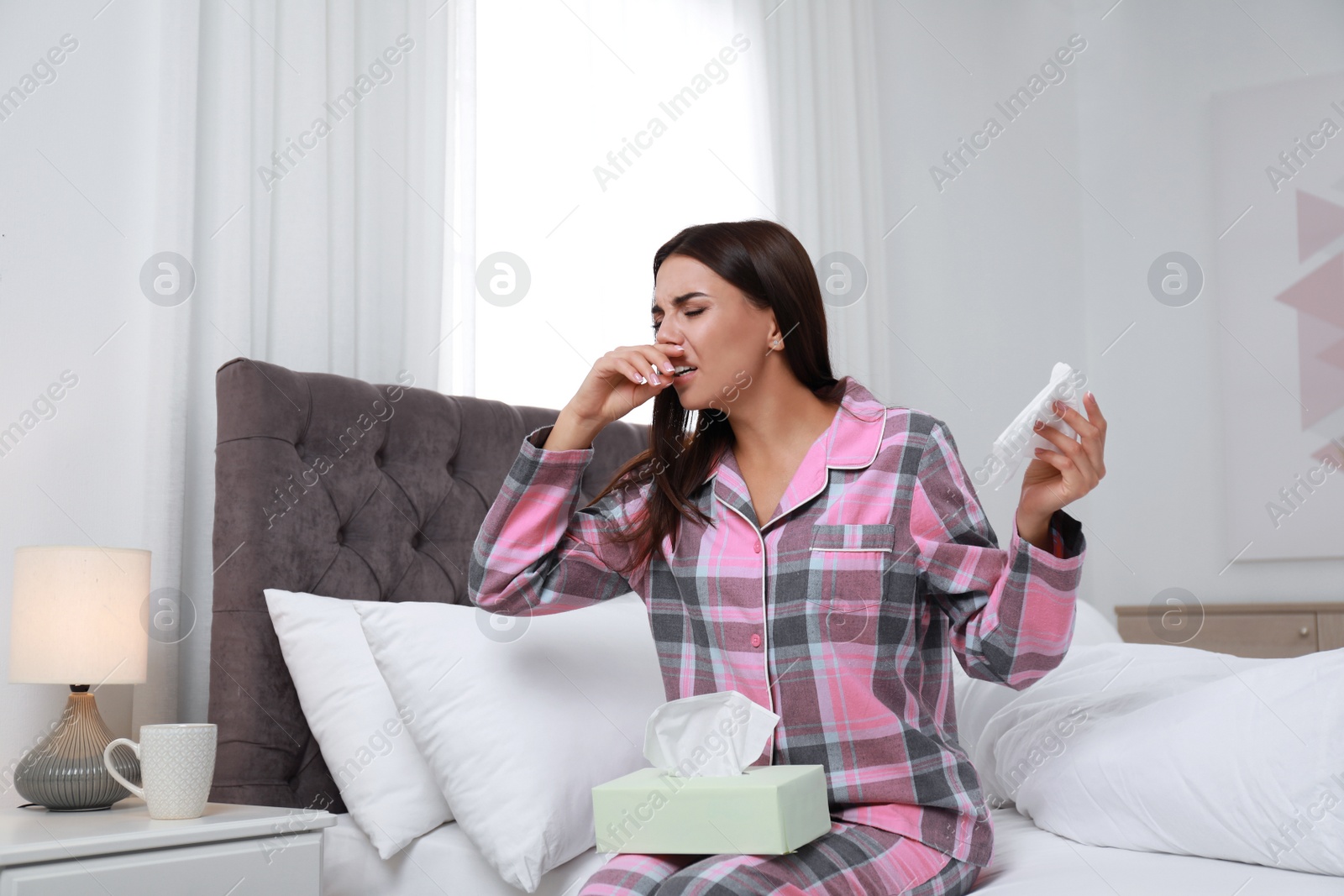 Photo of Young woman suffering from allergy in bedroom