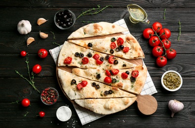 Photo of Delicious focaccia bread with olives and tomatoes on black wooden table, flat lay