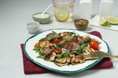 Photo of Delicious salad with beef tongue, grilled vegetables, peach, blue cheese and fork served on white table