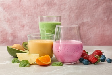 Photo of Glasses with healthy detox smoothies and ingredients on table