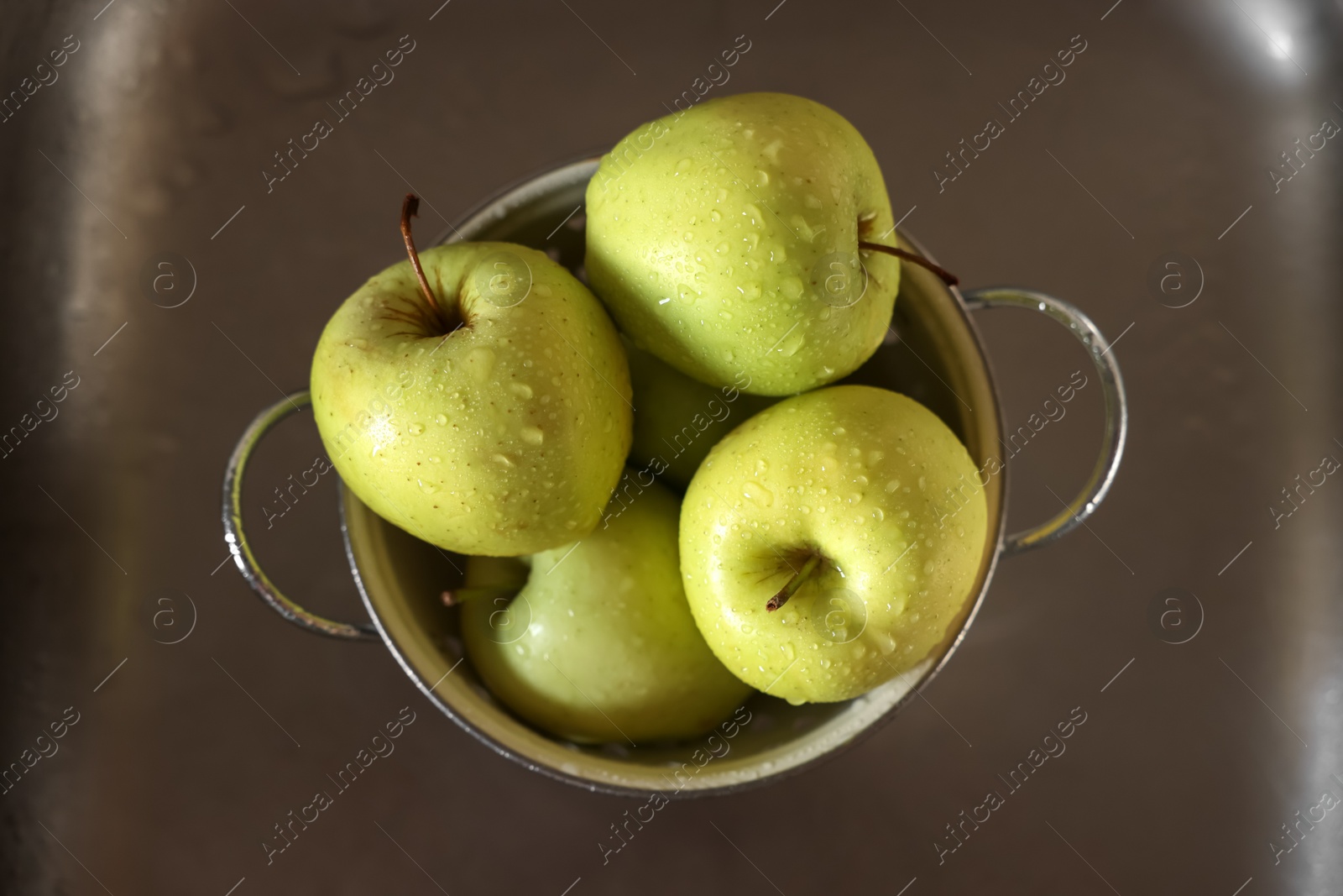 Photo of Fresh wet apples in metal colander inside sink, top view