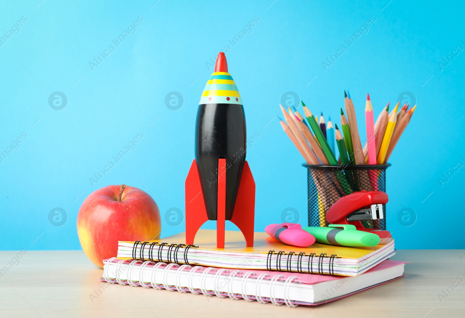 Photo of Bright toy rocket and school supplies on wooden table