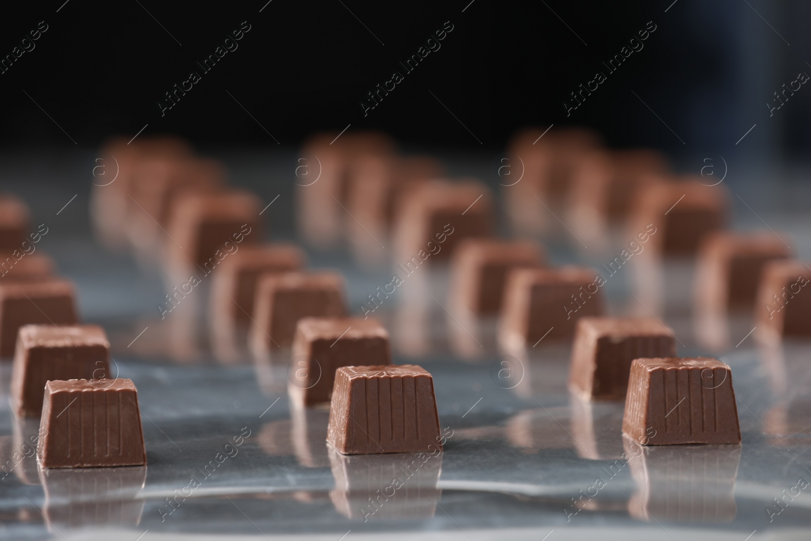 Photo of Many delicious chocolate candies on production line, closeup