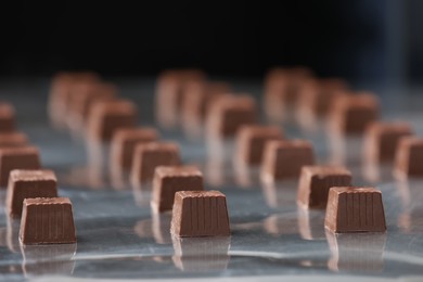 Photo of Many delicious chocolate candies on production line, closeup