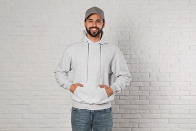 Photo of Portrait of young man in sweater at brick wall. Mock up for design