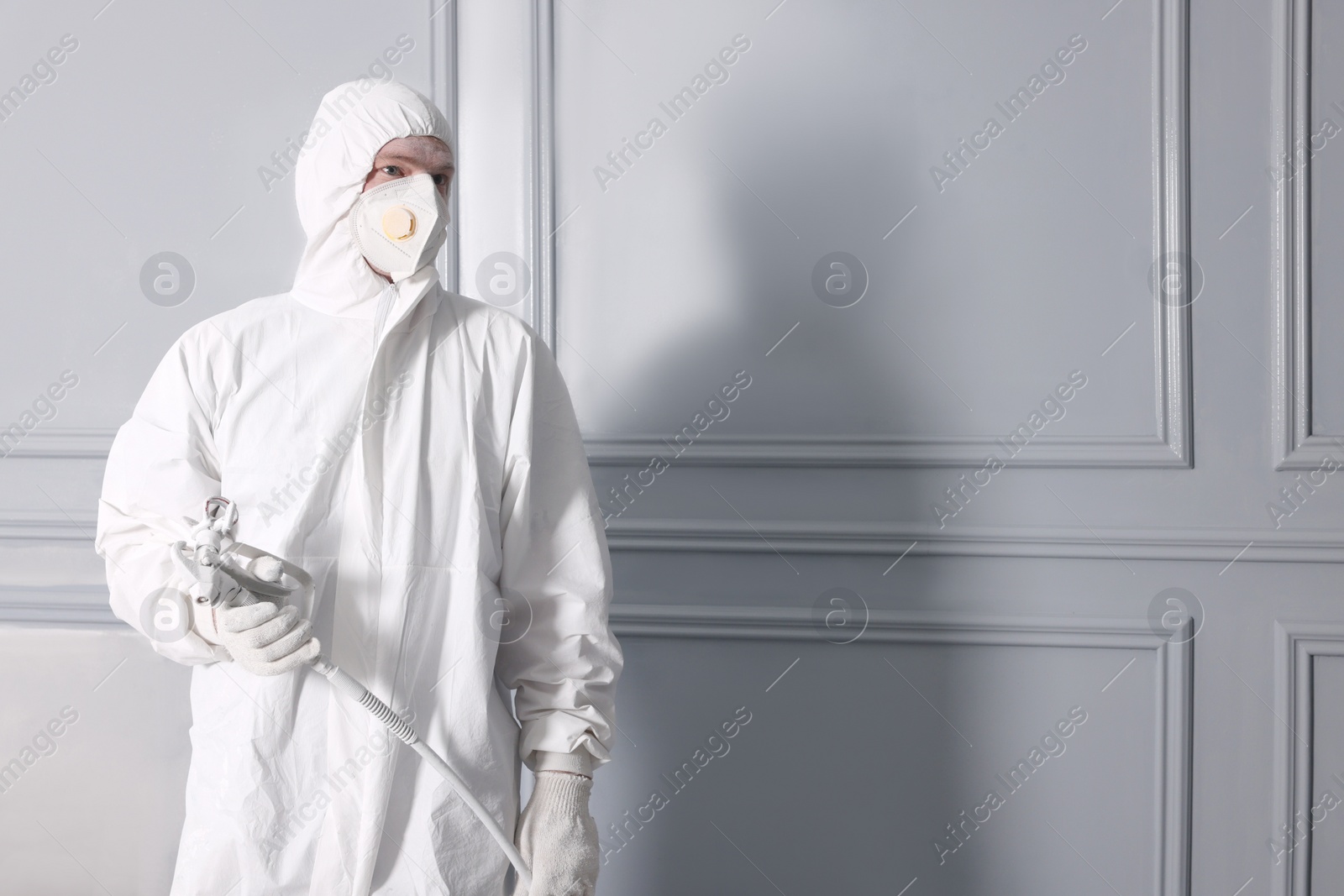 Photo of Decorator with spray paint near fresh dyed walls, space for text