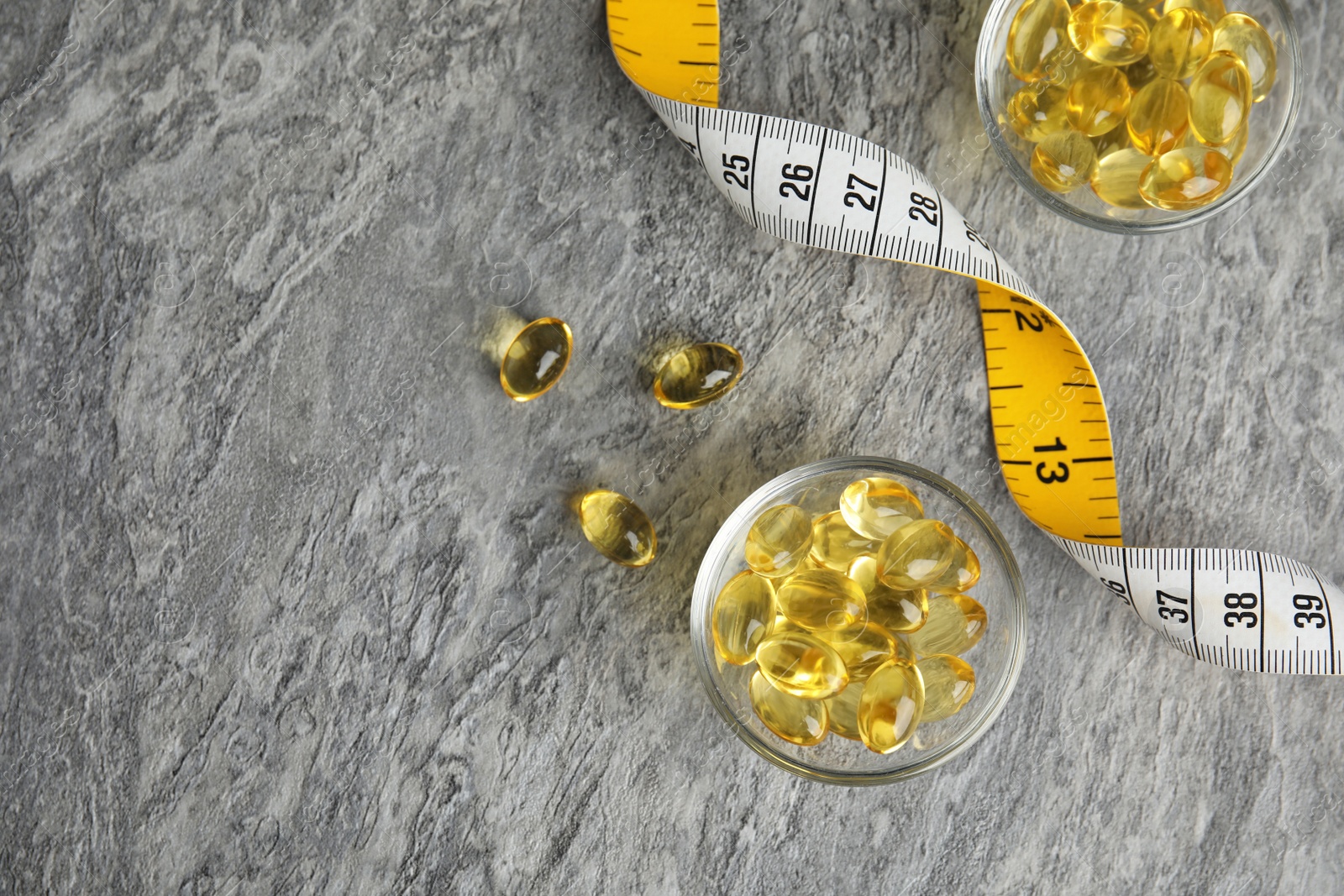Photo of Cod liver oil pills with measuring tape and space for text on gray background, flat lay