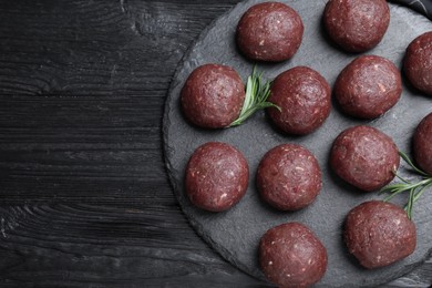 Photo of Many fresh raw meatballs on black wooden table, top view. Space for text