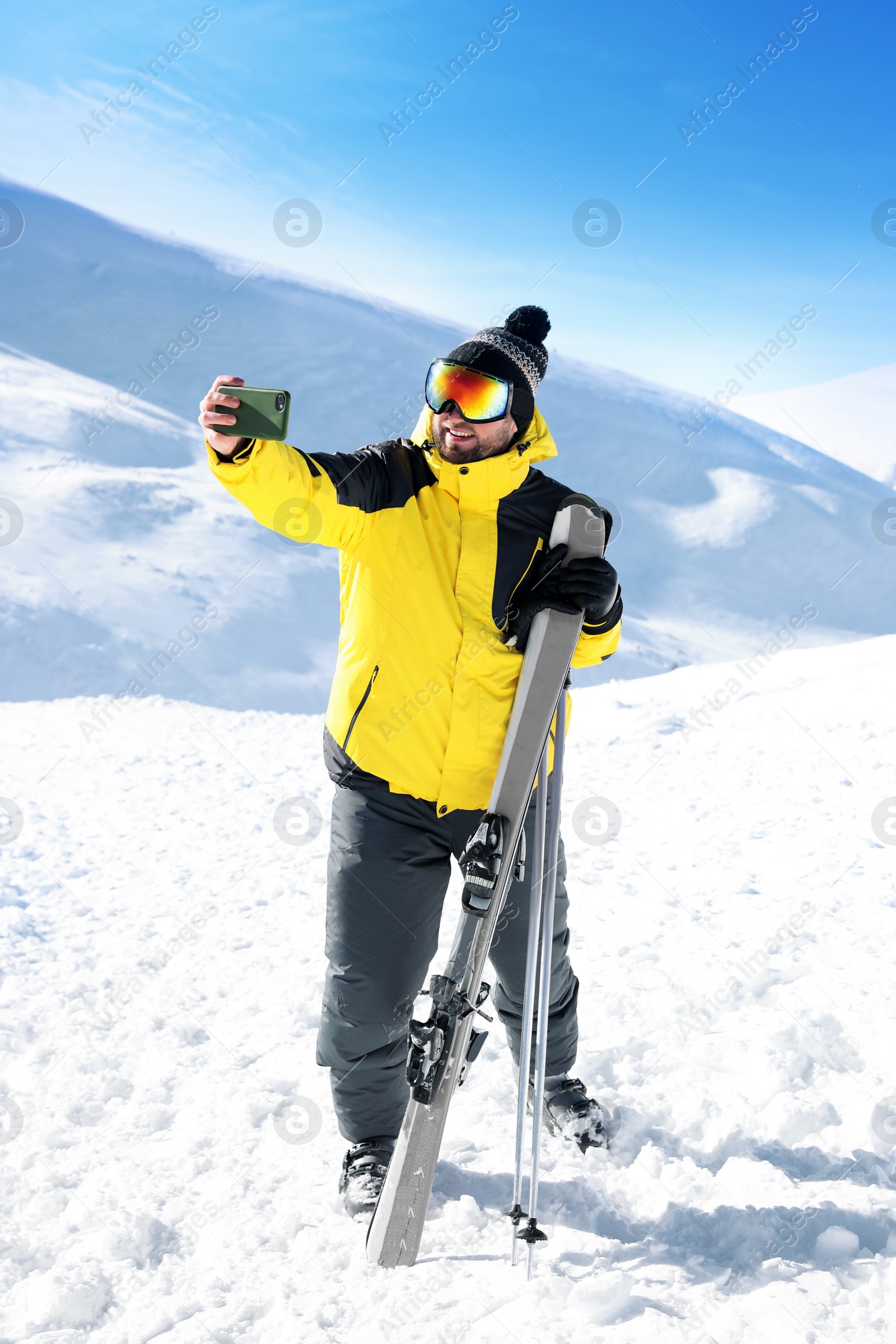 Photo of Young man with ski taking selfie on hill. Winter vacation