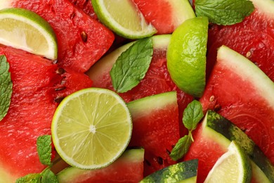 Photo of Cut juicy watermelon with lime and mint leaves as background, top view