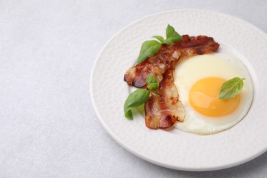 Fried egg, bacon and basil on light grey table, space for text