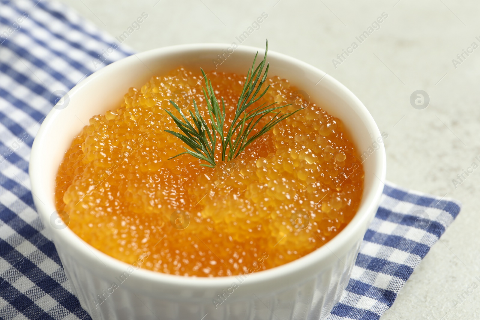 Photo of Fresh pike caviar and dill in bowl on light grey table, closeup