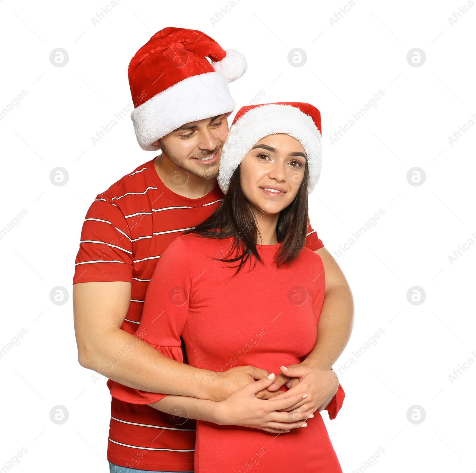 Photo of Young happy couple with Santa hats on white background. Christmas celebration