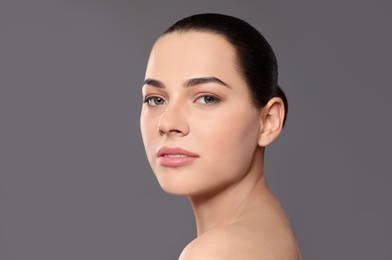 Photo of Portrait of young woman with beautiful face and natural makeup on color background