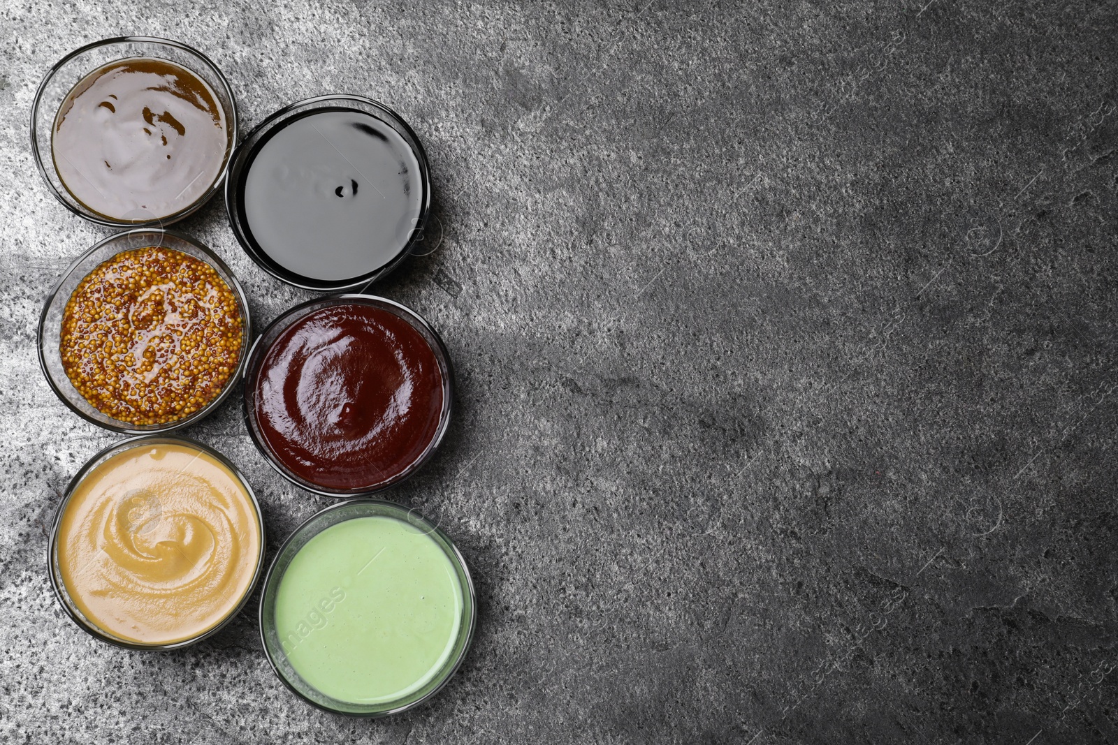 Photo of Many different sauces on grey table, flat lay. Space for text