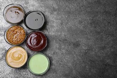 Photo of Many different sauces on grey table, flat lay. Space for text