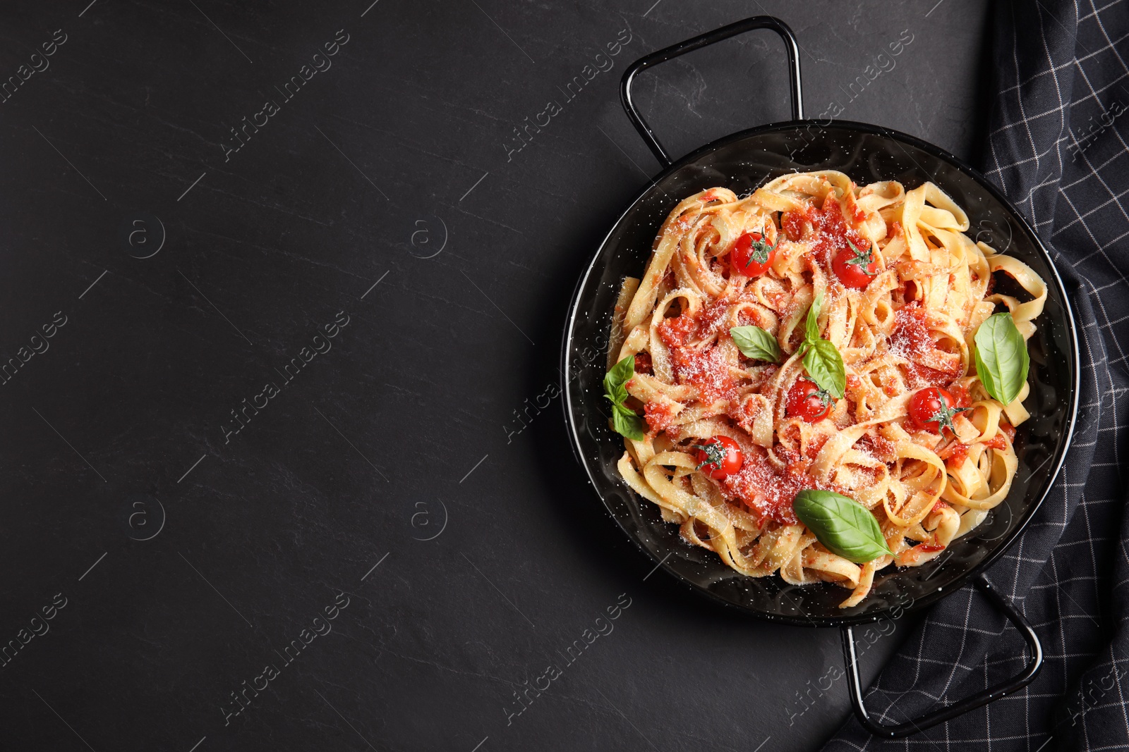 Photo of Tasty pasta and napkin on black table, flat lay. Space for text