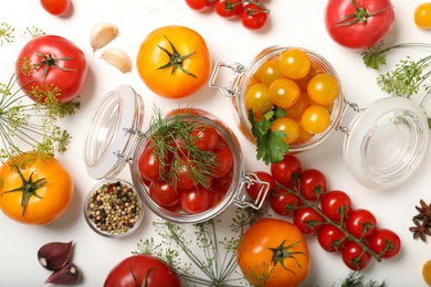 Photo of Pickling jars with fresh tomatoes on white table, flat lay