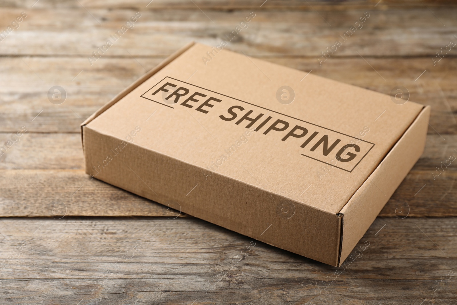 Image of One closed cardboard box on wooden table. Free shipping