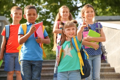 Cute little children with backpacks and notebooks outdoors. Elementary school