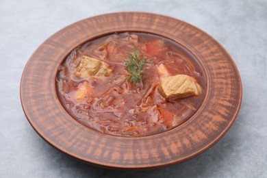 Photo of Bowl of delicious borscht on light grey table