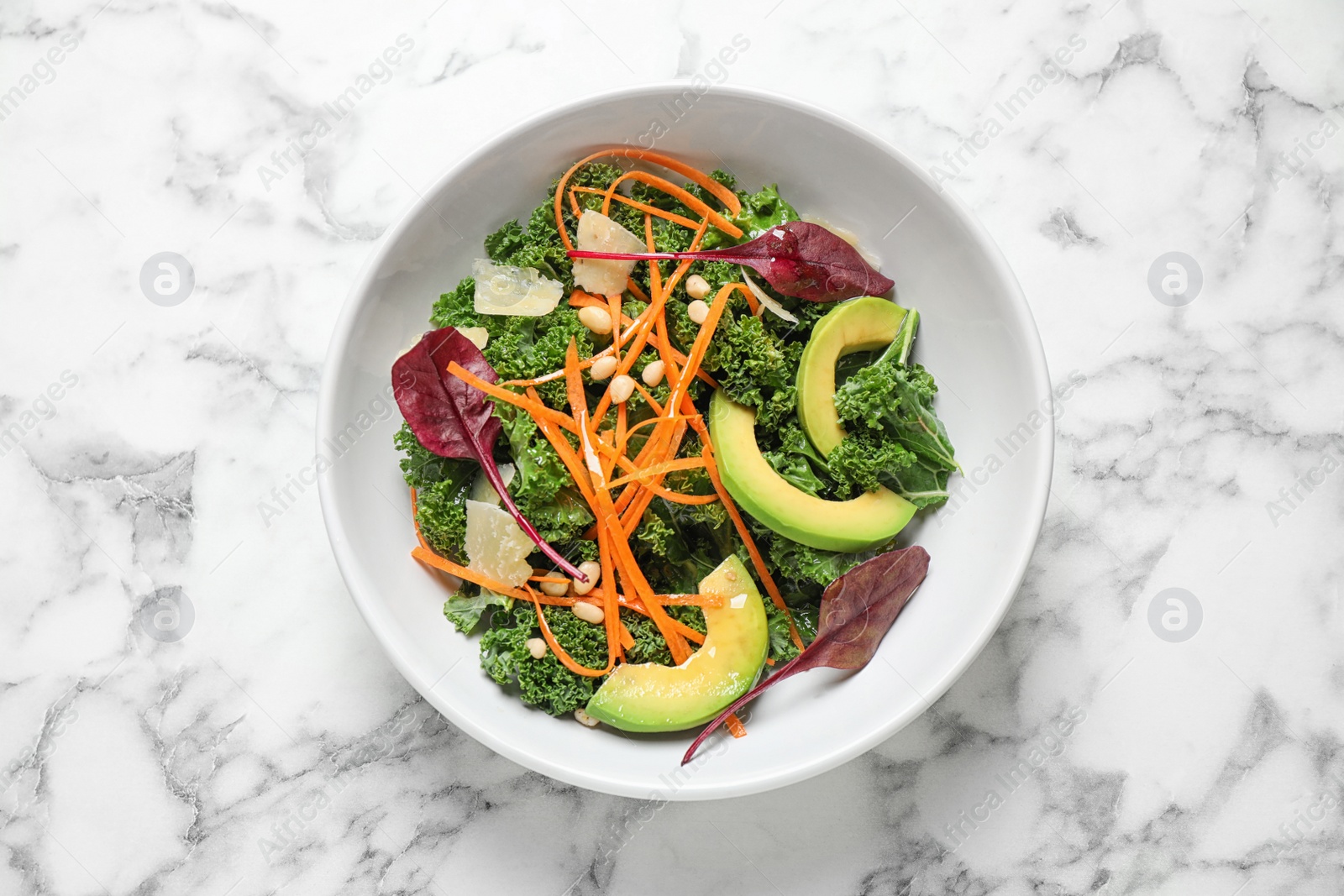 Photo of Tasty fresh kale salad on marble table, top view