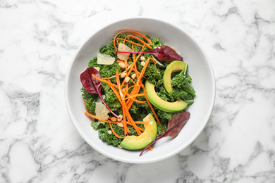 Photo of Tasty fresh kale salad on marble table, top view