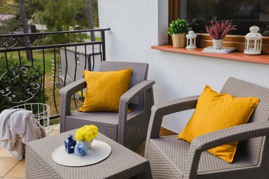 Orange pillows and yellow chrysanthemum flowers on rattan garden furniture outdoors