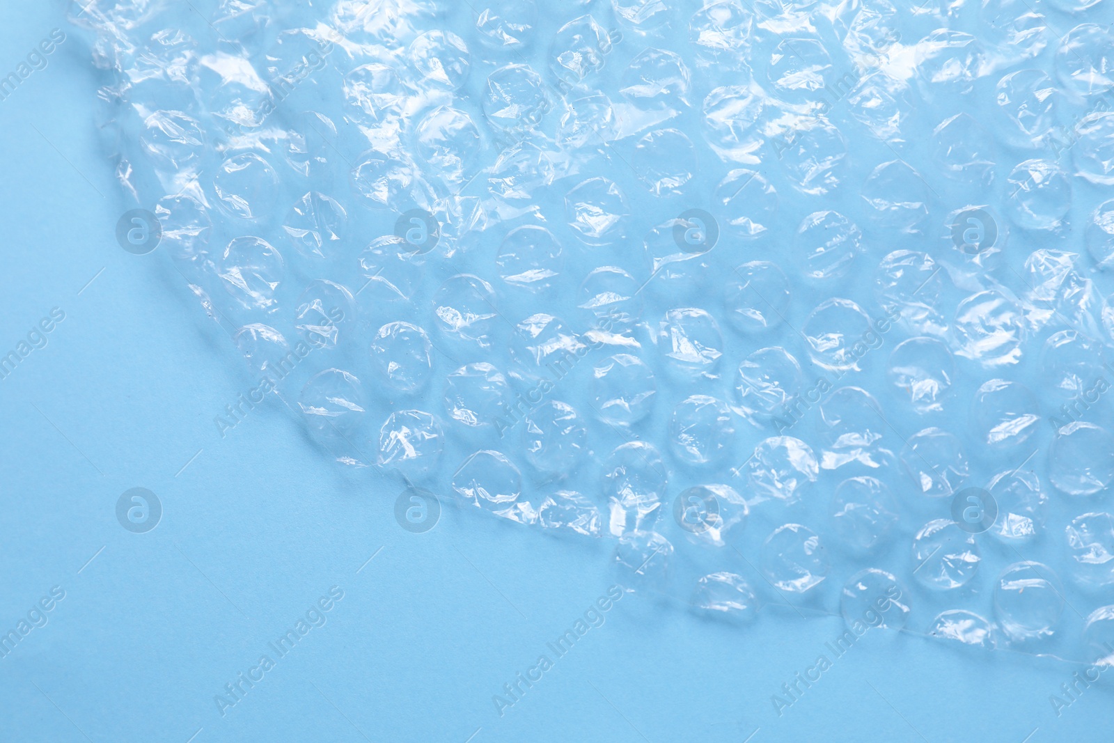 Photo of Transparent bubble wrap on light blue background, top view. Space for text